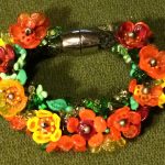 Strikket armbånd med orange blomster